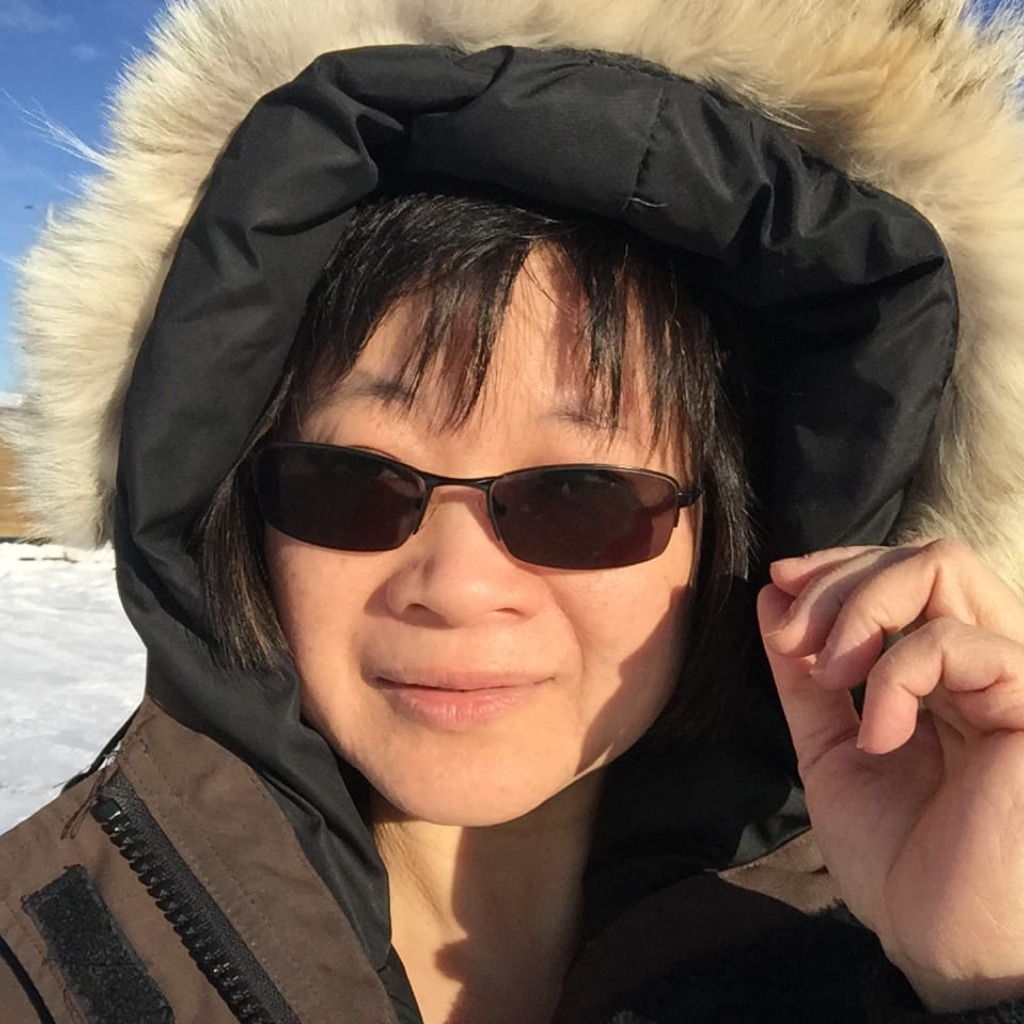 Janice Seto, Chamber Director, outside in teh winter, wearing a parka and sunglasses, smiling at the camera