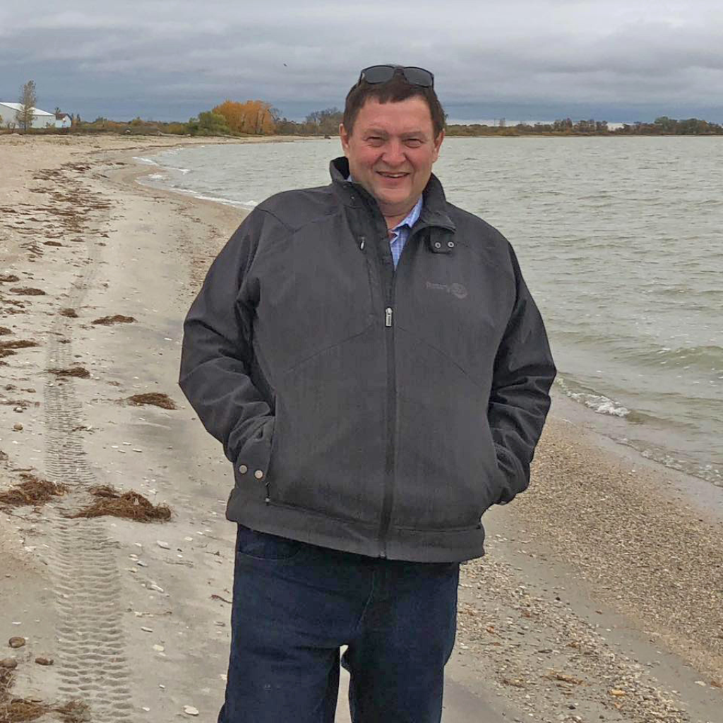 Jim Berscheid, Chamber Director, standing at the beach on a cool day, smiling at the camera