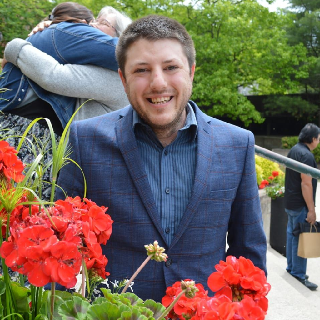 Johnathan Lalonde, Chamber Director, dressed well, surrounded by flowers, smiling at the camera